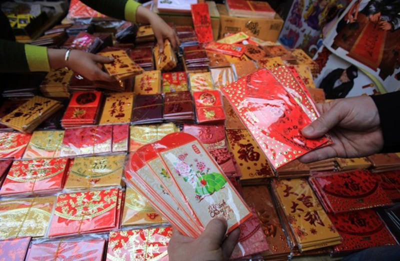 Shoppers select packages of red envelopes for giving lucky money to young people and employees during the Lunar New Year, in the old quarter of Hanoi, Vietnam, Feb. 6, 2016. (Hau Dinh/AP)