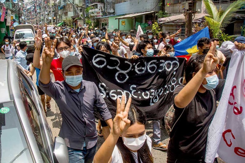 Anti-coup protesters carry a banner that reads "What are these? We are Yangon residents!" as they march during a demonstration in Yangon, Myanmar. (Associated Press)