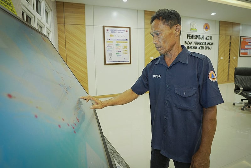 Tsunami survivor Arif Munandar checks the Warning Receiver System in his office in Aceh province, Indonesia, Dec. 5, 2024.