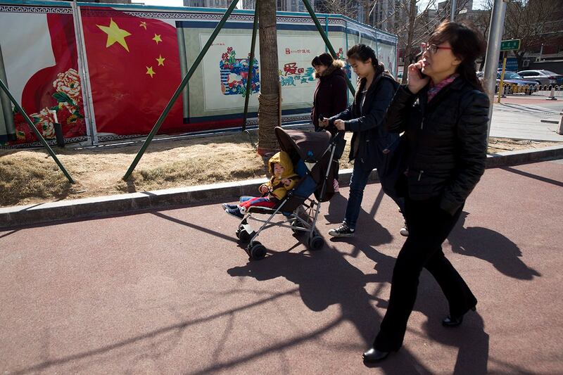 北京市一名妇女推着婴儿推车行经一处政府宣传壁画。 (美联社资料图片)