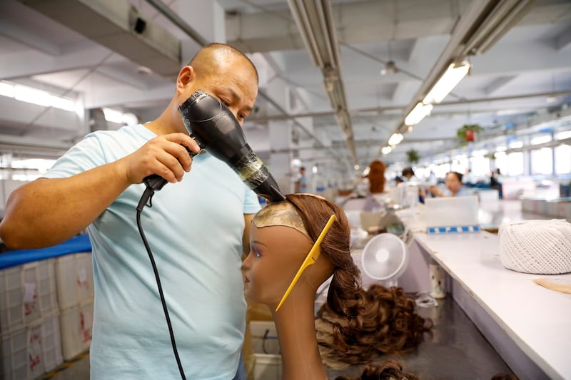 An employee works on the production line at a workshop of wig, June 4, 2024 in Xuchang, Henan, China. (Kan Li/China News Service/VCG via Getty Images)