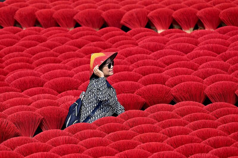 A tourist poses in front of incense sticks drying in Quang Phu Cau village near Hanoi on Jan. 21, 2025.