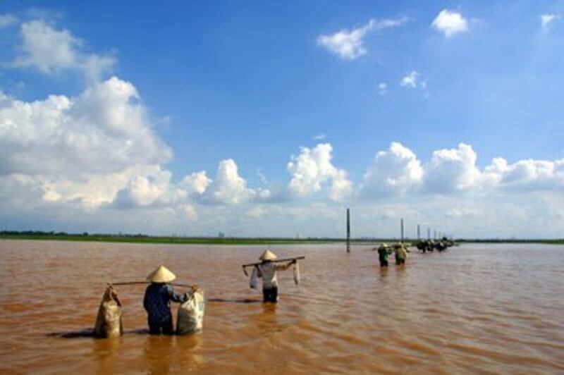 Người dân đi trên một con đường bị ngập lụt do sông Hồng ở Hà Nội. AFP photo 