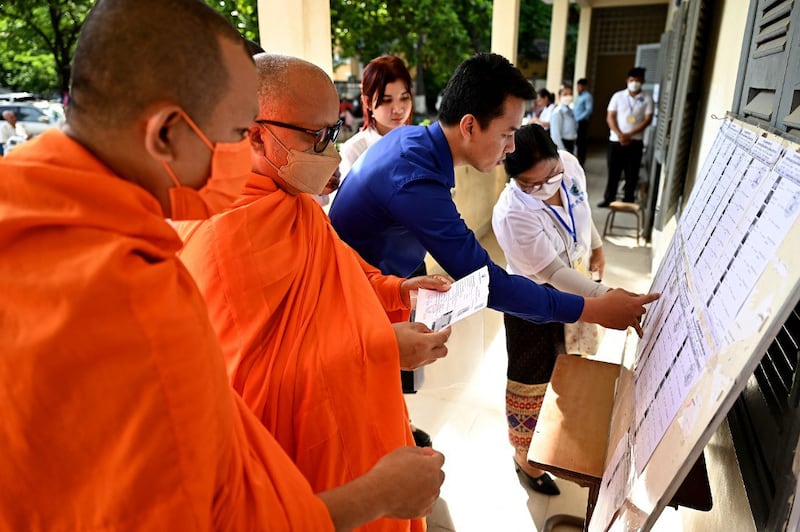 Buddhist monks look at voters lists at a polling station in Phnom Penh on July 23, 2023 during the general elections. (Photo by TANG CHHIN Sothy / AFP)