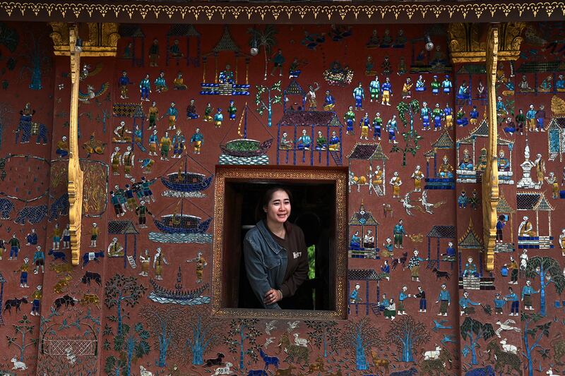 A woman looks out  a window of a pagoda shrine in Luang Prabang, Laos,  Jan. 28, 2024.