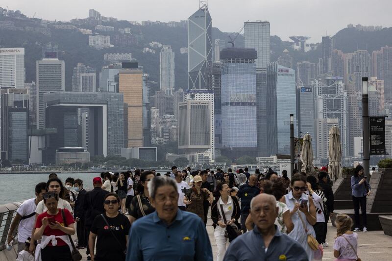 Mainland tourists and other people walk along the promenade next to Victoria Harbour in Hong Kong. Credit: AFP