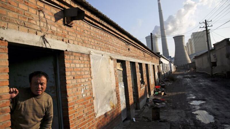 A migrant worker steps out of his accommodation in an area next to a coal-fired power plant in Beijing during a smog-free day and the last day of the city's first 'red alert' for air pollution, Dec. 10, 2015.