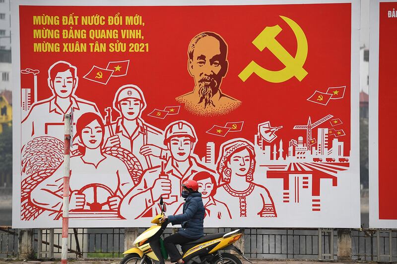 A man rides past a poster for the 13th National Congress of the Communist Party of Vietnam in Hanoi on Jan. 22, 2021. (Nhac Nguyen/AFP)