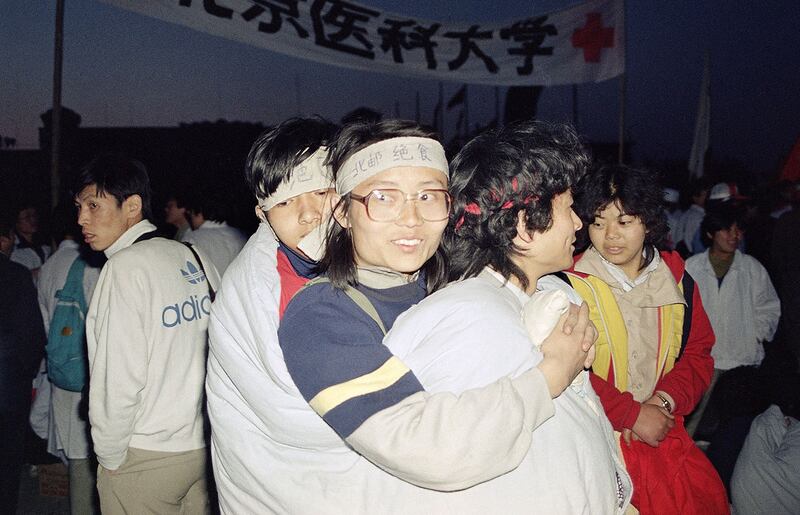 "1989年5月15日星期一，在北京天安门广场上，寒冷的夜晚，罢工的北京大学学生三人挤在一个袋子里。（美联社）