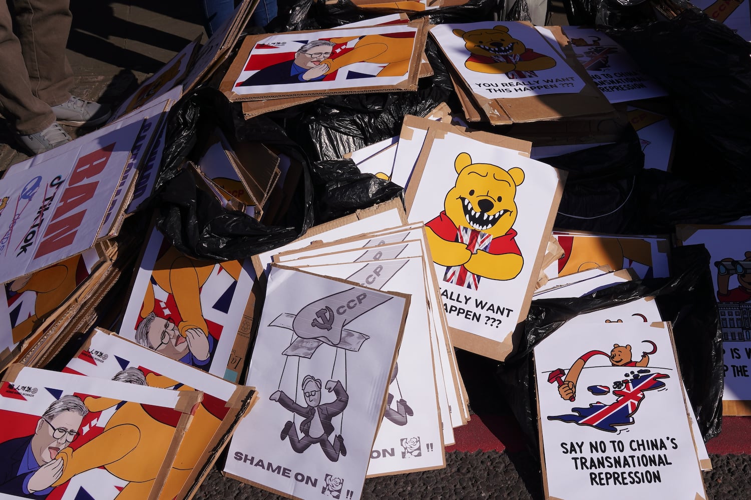 Anzeichen, die den britischen Premierminister Keir Starrer und den chinesischen Präsidenten Xi Jinping als Winnie the Pooh auf Demonstranten an dem vorgeschlagenen Standort des chinesischen „Mega-Embassy“ in London am 15. März 2025 warten.