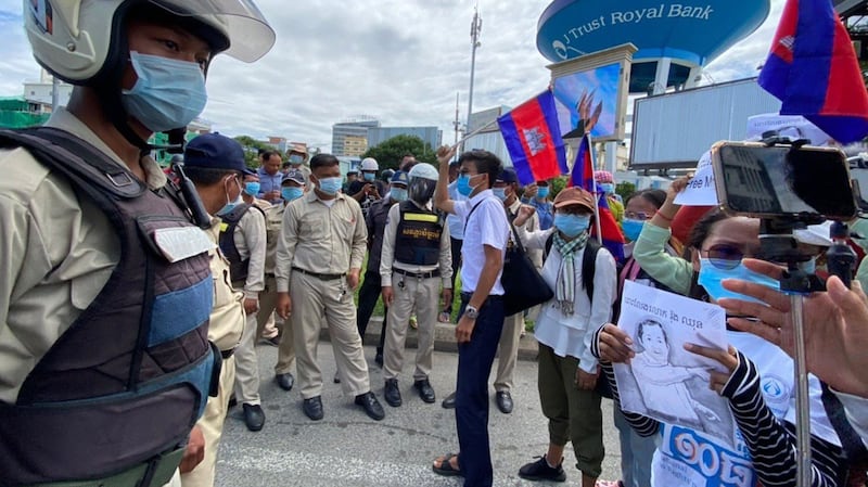 Protesters demanding the release of union leader Rong Chhun are monitored by security forces during a demonstration in front of the Phnom Penh Municipal Court in Phnom Penh, Aug. 5, 2020.