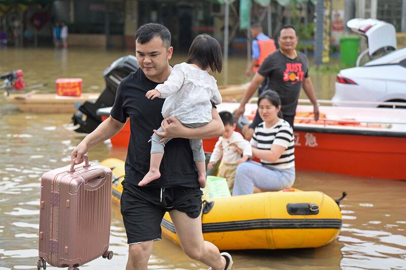 2024年4月28日，广东省清远市暴雨过后，居民从洪水泛滥的地区撤离，涉水而过。（法新社）