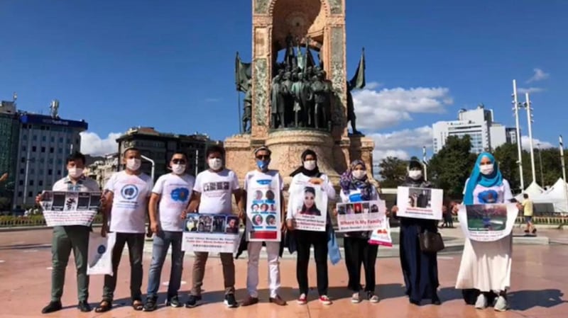 Uyghurs wearing T-shirts with images of missing relatives pose for a photo in front of the Republic Monument on Taksim Square in Istanbul, Aug. 17, 2020.