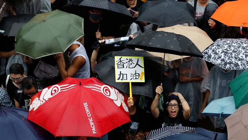 资料图片：2019年8月18日，香港反送中大游行，市民手持标语牌：“香港人 加油”。（美联社）