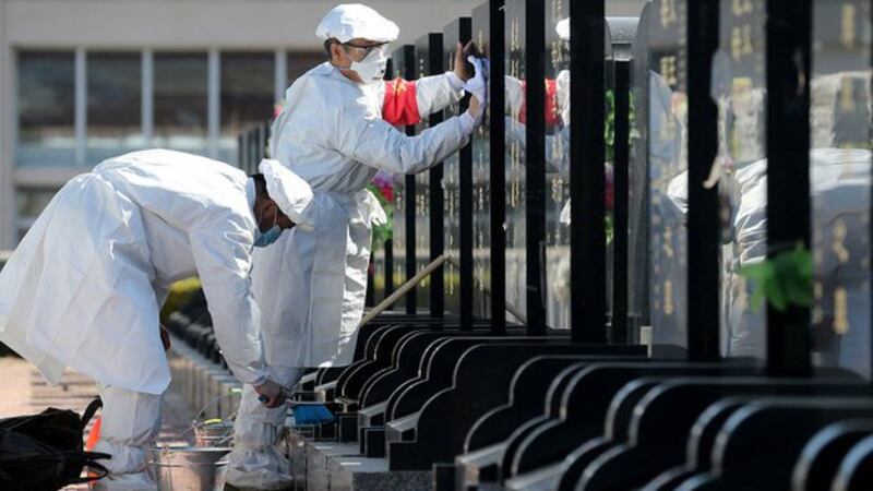 身穿防护服的工作人员正在清洗武汉安葬新冠死者的一个墓地（法新社资料图）