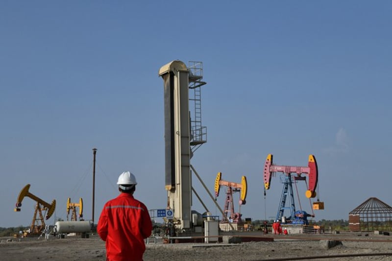 Workers are seen near pumpjacks at a China National Petroleum Corp oil field in Bayingol in northwestern China's Xinjiang region, Aug. 7, 2019. (Reuters)