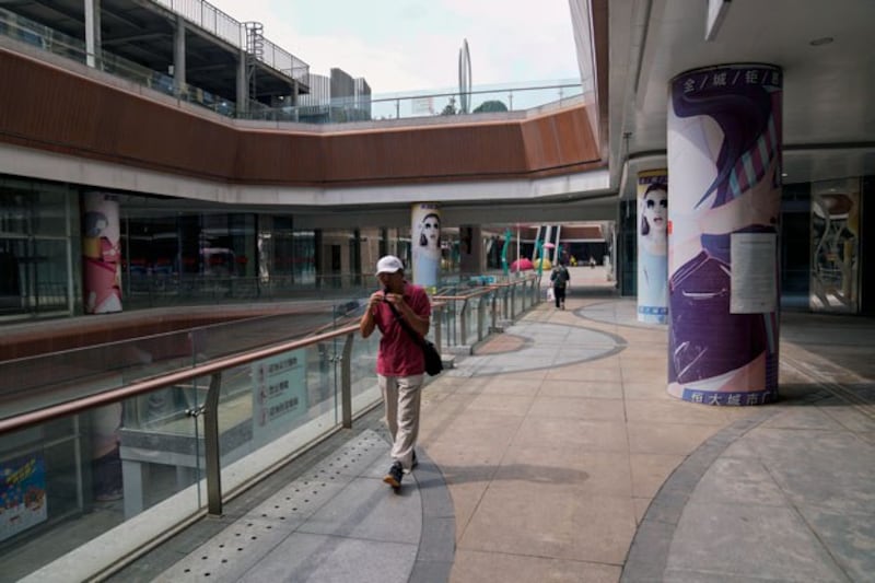 A man plays a harmonica while walking by a deserted Evergrande city plaza in Beijing, China, on Sept. 18, 2023. (Andy Wong/AP)