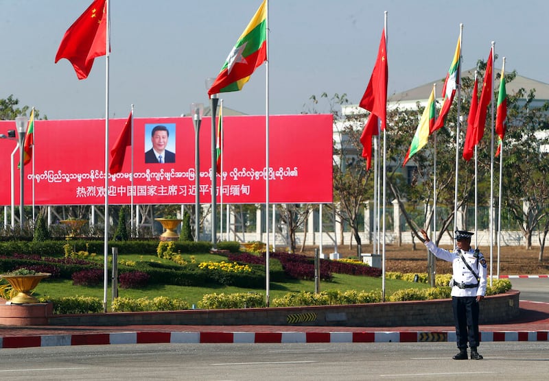 A traffic police officer directs traffic near a welcoming billboard to Chinese President Xi Jinping, in Naypyidaw