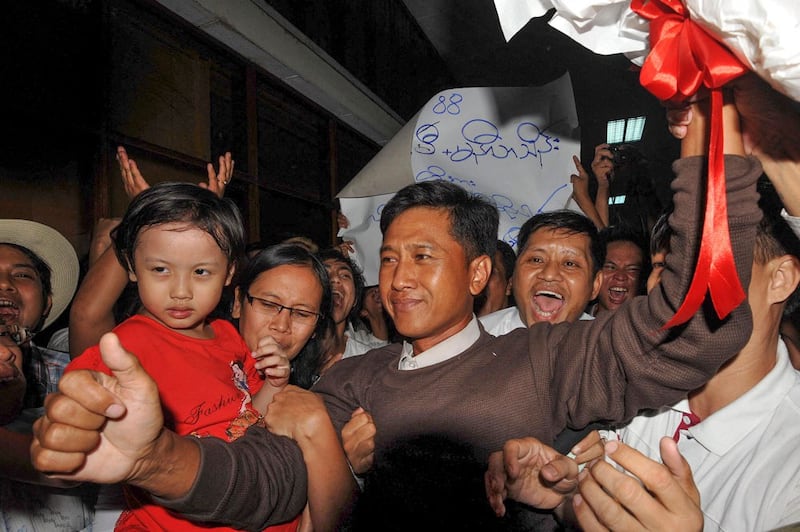 Myanmar political prisoner Kyaw Min Yu (C), known as Jimmy, and his wife Ni Lar Thein (L) holding her child, both members of the 88 Generation student group, celebrate upon their arrival at Yangon international airport following their release from detention on January 13, 2012. Myanmar pardoned prominent dissidents, journalists and a former premier on January 13 under a major prisoner amnesty, intensifying a surprising series of reforms by the army-backed regime. AFP PHOTO/Soe Than WIN Soe Than WIN / AFP