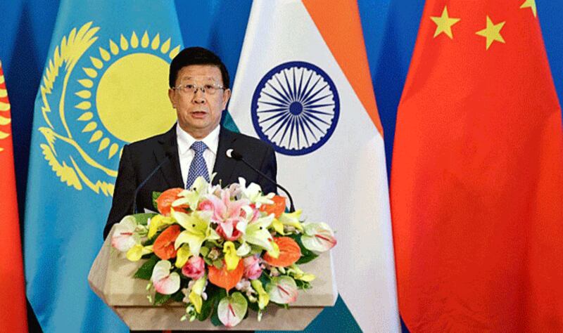 China's Minister of Public Security Zhao Kezhi stands in front of national flags before a plenary meeting of the Shanghai Cooperation Organization National Security Council Secretaries summit in Beijing, May 22, 2018. Credit: AFP