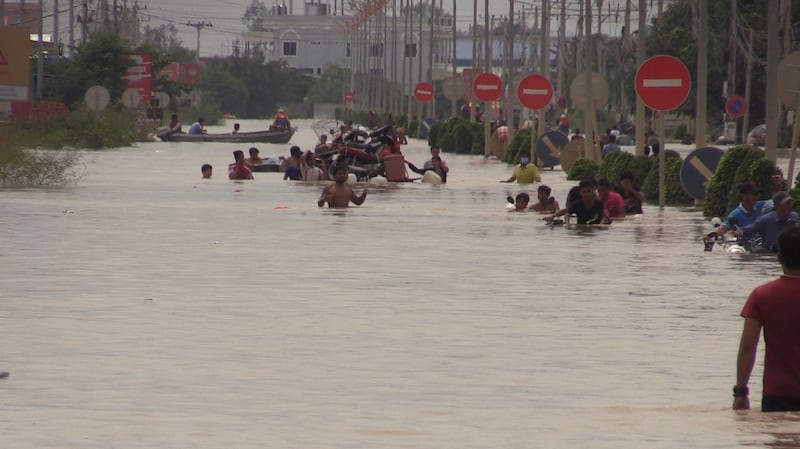 Residents wade through chest-high floodwaters in the streets of Phnom Penh, Oct. 15, 2020.