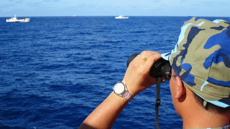 A crewman from a Vietnamese coast guard ship looks out at sea as Chinese coast guard vessels give chase to Vietnamese ships close to an oil rig in the South China Sea, July 15, 2014. Credit: Reuters