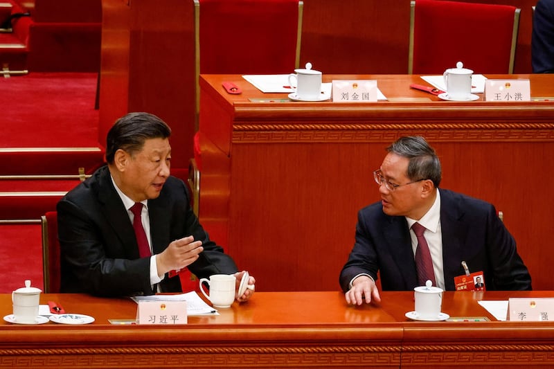 Chinese President Xi Jinping talks to Li Qiang, who is expected to become China's new premier, during the Third Plenary Session of the National People's Congress at the Great Hall of the People, in Beijing, Friday, March 10, 2023. Credit: Pool via Reuters