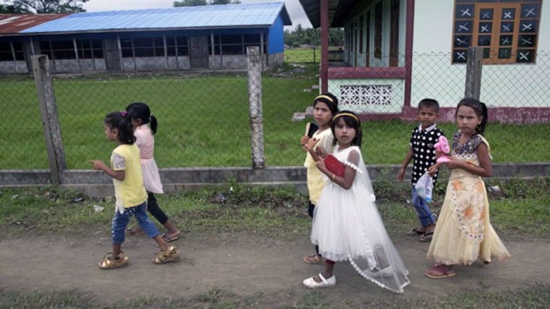 Rohingya children celebrating the Islamic holiday Eid al-Adha walk along a dirt road in Shwe Zar village during a government-organized visit for journalists in Maungdaw township, western Myanmar's Rakhine state, Aug. 23, 2018.