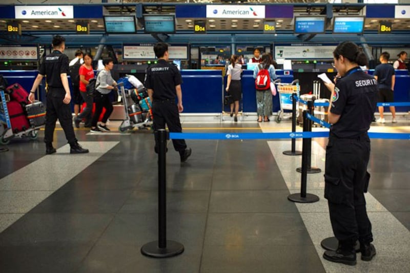 Chinese security personnel watch as travelers check in for flights at the Beijing Capital International Airport in Beijing, China, July 6, 2018. (Mark Schiefelbein/AP)