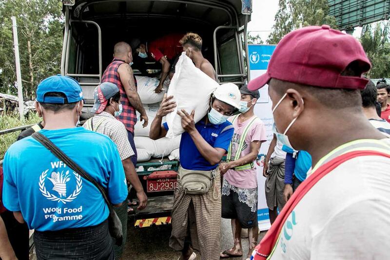 People receive bags of rice from the World Food Program on May 21, 2021 as part of efforts to supply food to residents of poor communities on the outskirts of Yangon. (AFP)