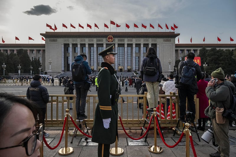 A member of the People's Armed Police is surrounded by journalists as he stands guard outside the Great Hall of the People in Beijing on March 4, 2025.