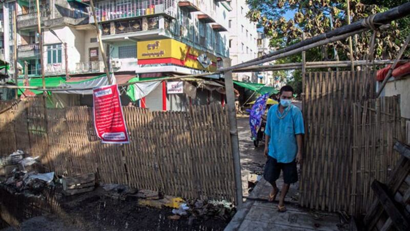 A man walks through a barrier blocking access to minor roads with a sign urging residents to stay at home in Myanmar's commercial hub Yangon, Sept. 11, 2020.