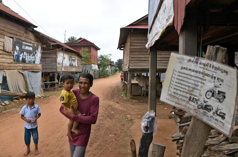 A man walks past advertisements promoting microfinance in Siem Reap province, Oct. 15, 2020. Cambodia Microfinance Association is a business group that represents the interests of the microfinance companies and lobbies on behalf of microfinance lenders. (Tang Chhin Sothy/AFP)