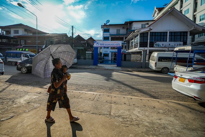 A woman carries a baby as she walks by the Nana Backpacker Hostel in Vang Vieng, Laos, Nov. 19, 2024.