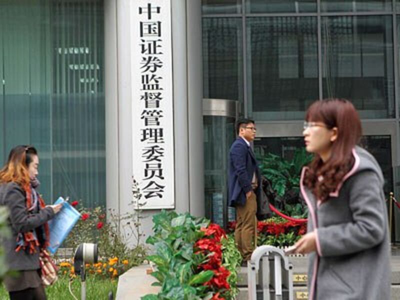 Chinese pedestrians walk by the headquarters of the China Securities Regulatory Commission in Beijing, Nov. 18, 2016.