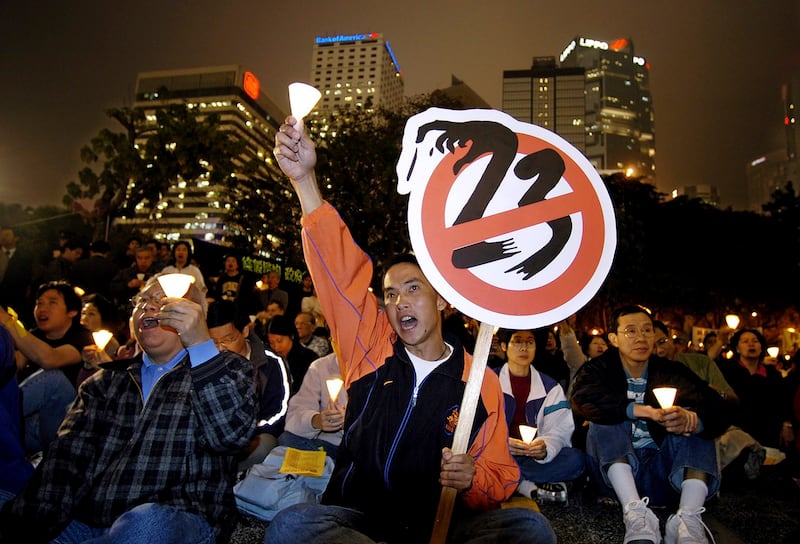 Pro-democracy activists shout slogans during a candlelight vigil at a Hong Kong park on Feb. 25, 2003. (Vincent Yu/AP)