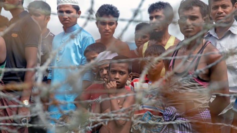 Rohingya refugees gather near a fence in the 'no-man's land' zone between the Myanmar and Bangladesh border as seen from Maungdaw district, western Myanmar's Rakhine state, Aug. 24, 2018. 