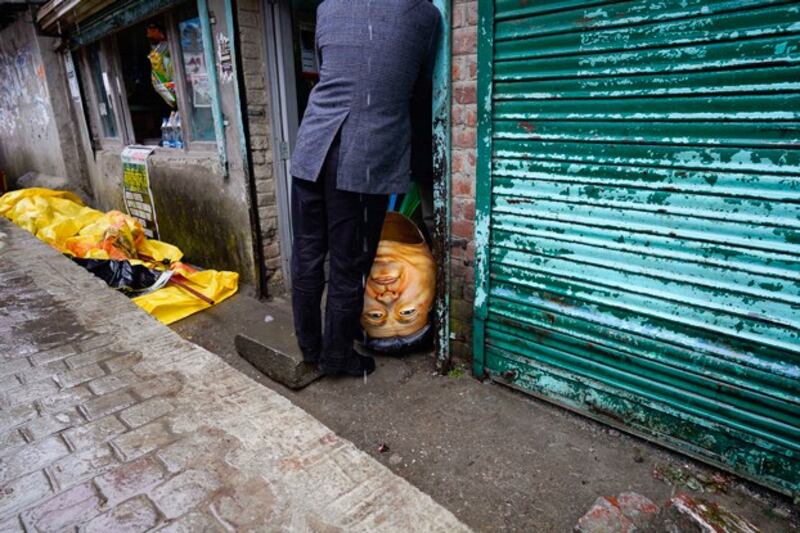 A hollow head in the likeness of Chinese President Xi Jinping is seen next to an exile Tibetan during a street protest against China's human rights abuses, in Dharmsala, India, Feb. 3, 2022. (Ashwini Bhatia/AP)