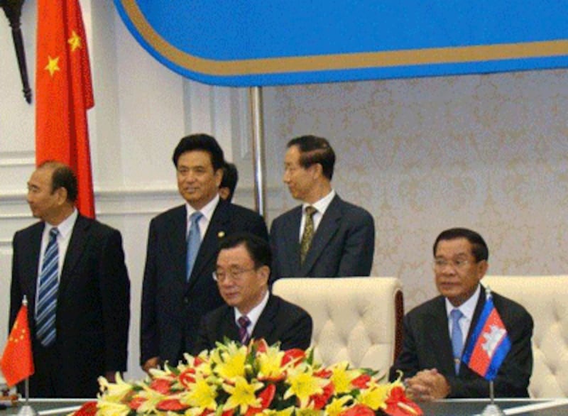 He Guoqiang, a top ruling Chinese Communist party official (seated left), and Cambodian Prime Minister Hun Sen (seated right) clinch a variety of deals in Phnom Penh, June 13, 2012.