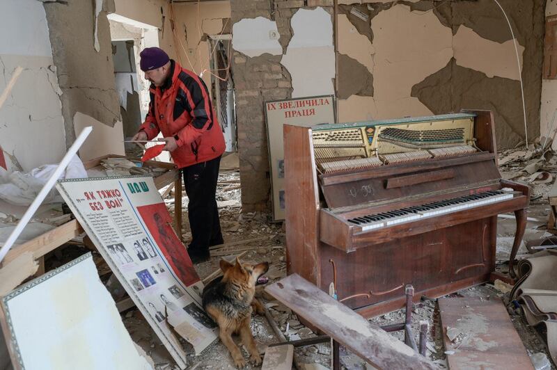 A man collects pictures from a school hit by Russian rockets in the southern Ukraine village of Zelenyi Hai between Kherson and Mykolaiv, less than 5 km (3 miles) from the front line, April 1, 2022. Credit: AFP