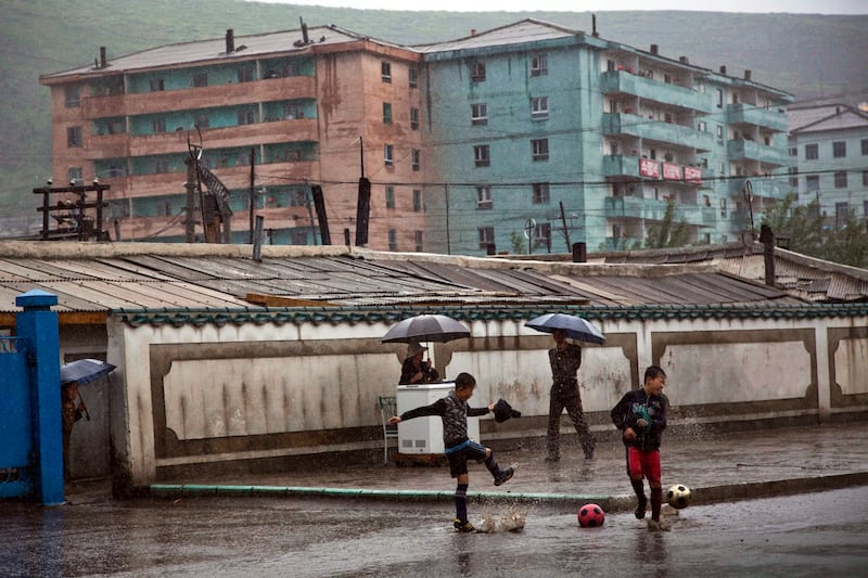 Boys play soccer in front of apartment buildings in the town of Hyesan in North Korea's Ryanggang province, June 16, 2014.