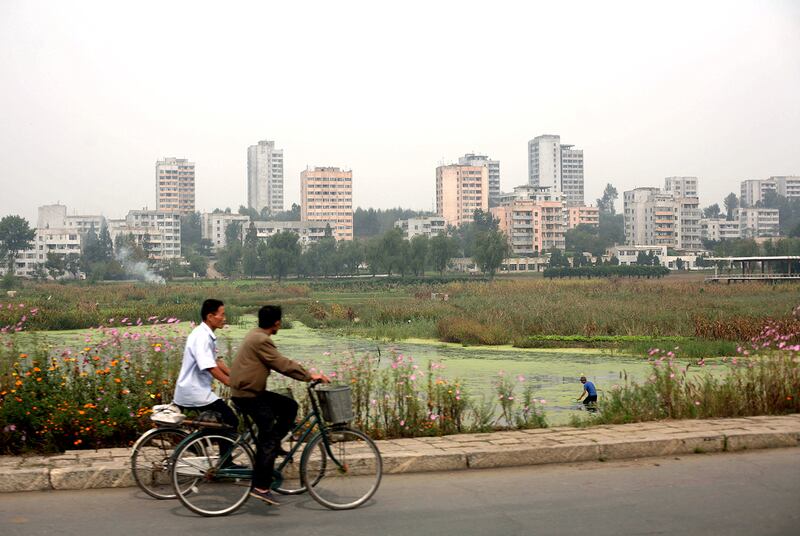 Men ride bicycles past the eastern coastal city of Nampo, North Korea Friday, Sept. 19, 2008.