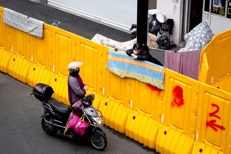 A woman leans on a barrier sealing off an area under lockdown in Shanghai, March 28, 2022. Credit: Reuters