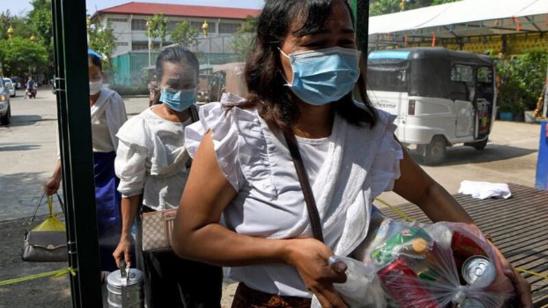 Cambodian women wearing face masks to protect themselves from the coronavirus walk through a gate equipped with disinfectant spray at a pagoda during the Khmer New Year in Cambodia's capital Phnom Penh, April 14, 2020.