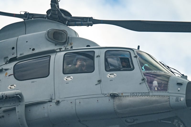 A Chinese Navy soldier films onboard an aircraft identified by the Philippine Coast Guard as Chinese Navy helicopter as they tails the Bureau of Fisheries and Aquatic Resources (BFAR) plane during an aerial reconnaissance flight at Scarborough Shoal in the South China Sea on February 18, 2025. (Photo by Jam STA ROSA / AFP)