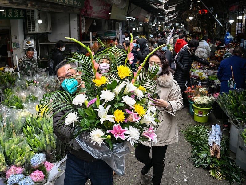 A man holds a flower arrangement at a flower market in Wuhan, China,  Jan. 21, 2023, ahead of the Lunar New Year.