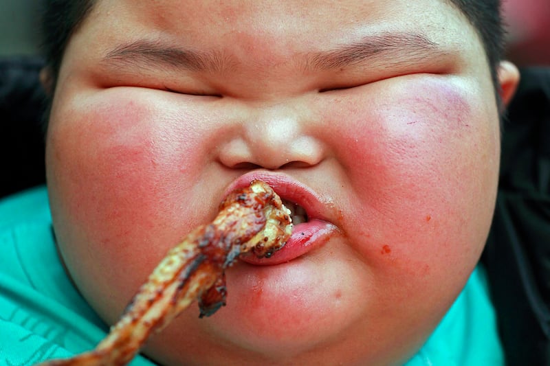 Lu Zhihao, 4, eats a roast chicken wing at a market in Foshan, Guangdong province March 29, 2011.