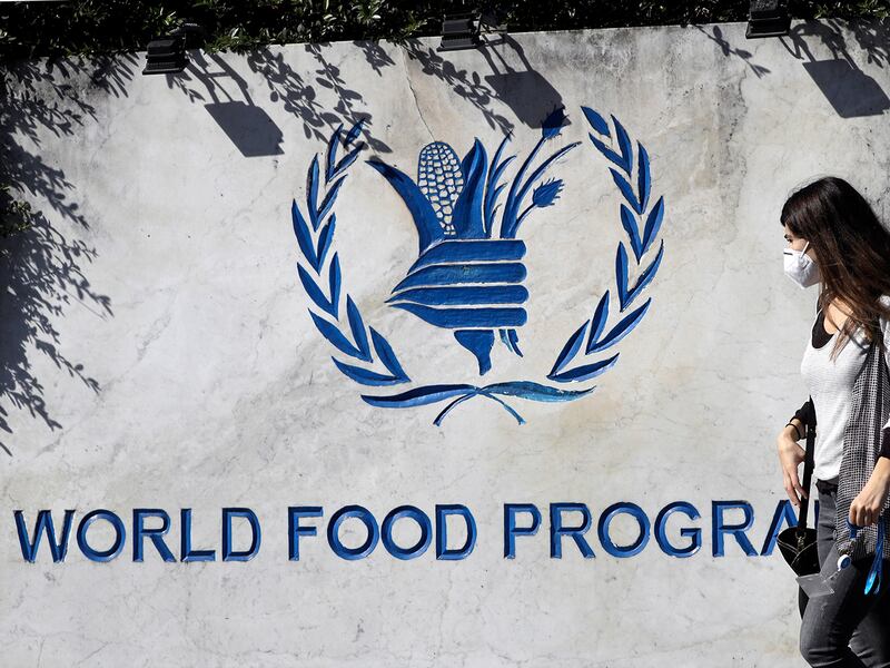 A woman walks past a sign at the entrance of the United Nations World Food Program headquarters in Rome, Oct. 9, 2020