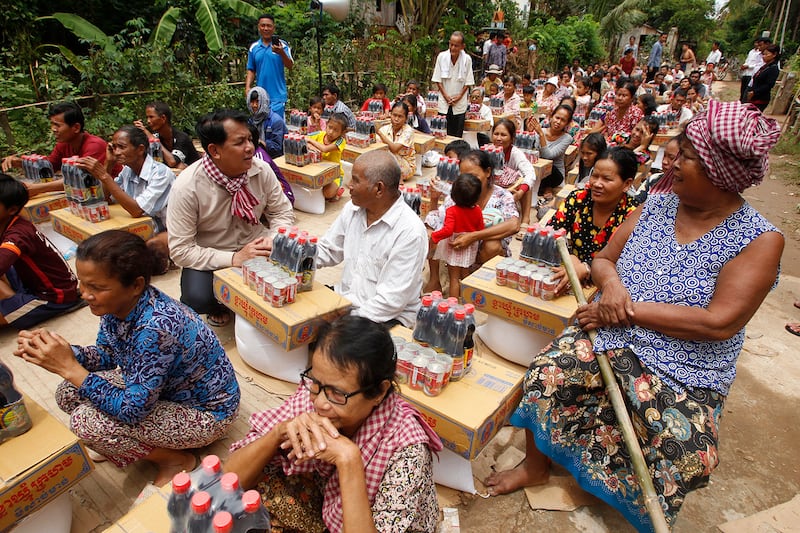 Phos Sovann, center left, the director general of Cambodia’s Ministry of Information, talks with villagers as they wait for gifts from the Cambodian Red Cross near the Mekong River northeast of Phnom Penh, Aug. 18, 2018.