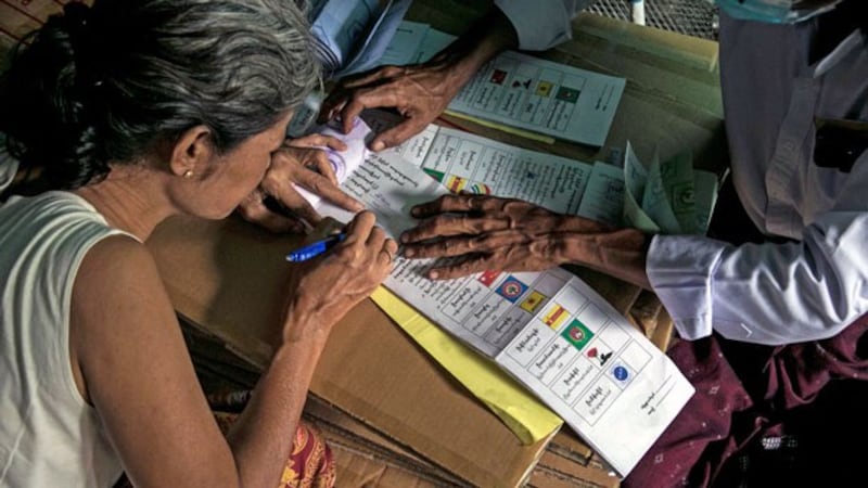 A senior citizen completes an election ballot inside her home during advance voting in Myanmar's commercial hub Yangon, Oct. 29, 2020.